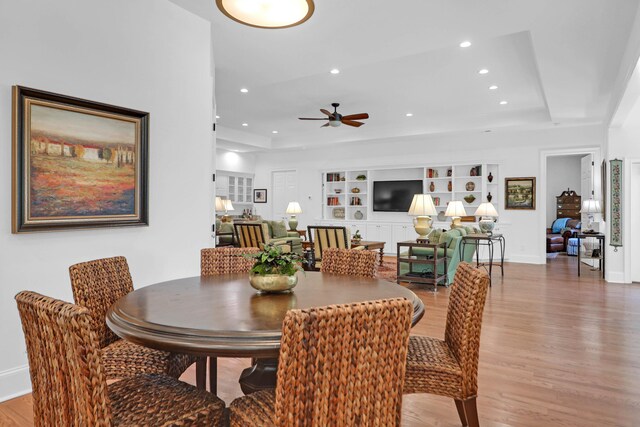 dining area with hardwood / wood-style floors, a tray ceiling, built in features, and ceiling fan