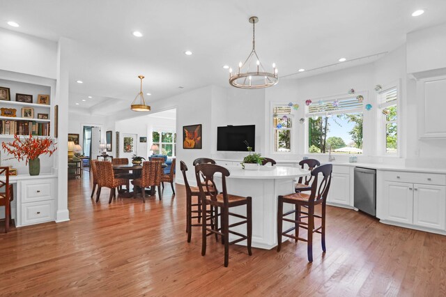 kitchen featuring decorative light fixtures, light hardwood / wood-style flooring, white cabinets, and a kitchen bar