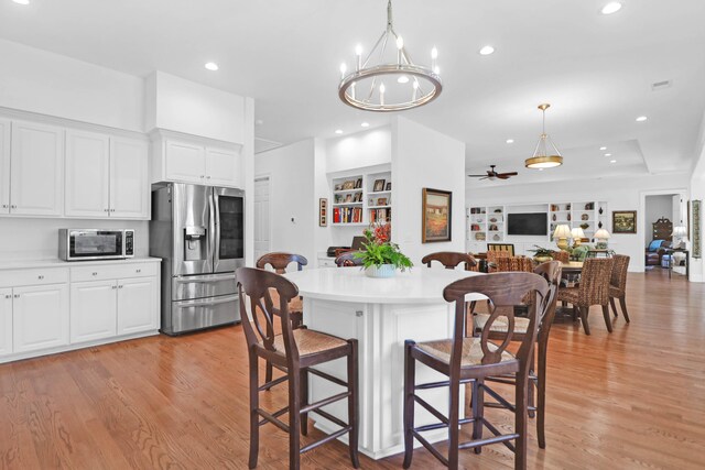 kitchen featuring stainless steel appliances, white cabinetry, light wood-type flooring, and a kitchen breakfast bar