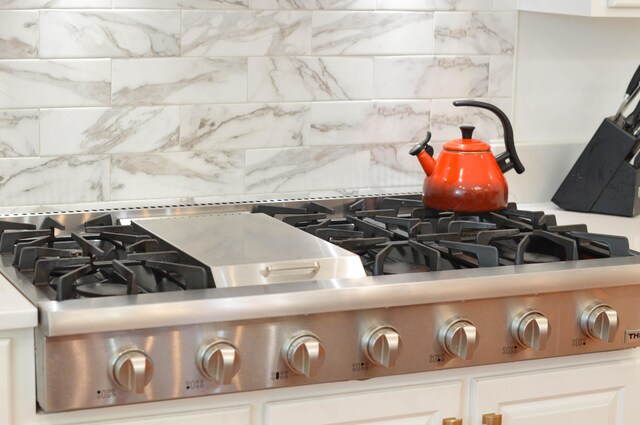 interior details featuring white cabinetry, tasteful backsplash, and gas stovetop