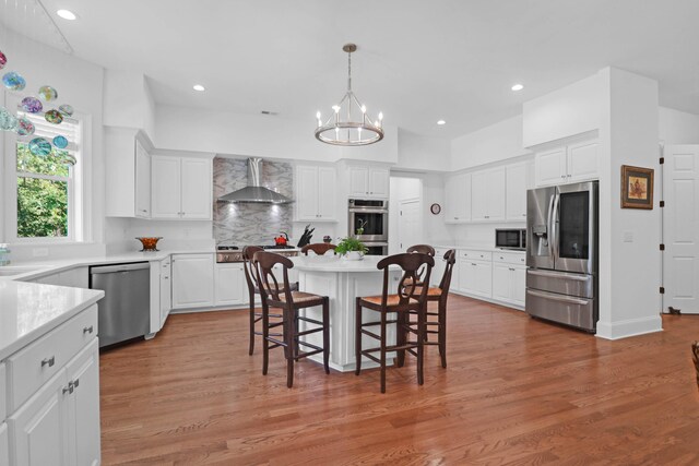 kitchen featuring white cabinetry, wall chimney exhaust hood, and appliances with stainless steel finishes