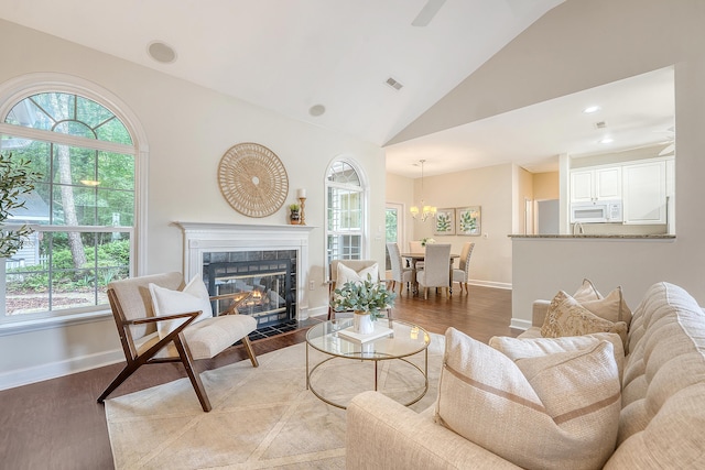 1148 Black Rush Cir, Mount Pleasant, SC 29466 - living room featuring wood finished floors, baseboards, a tiled fireplace, high vaulted ceiling, and a chandelier