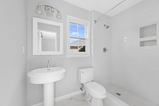 bathroom featuring toilet, sink, and a tile shower