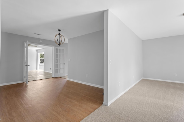 unfurnished room featuring a notable chandelier and hardwood / wood-style flooring