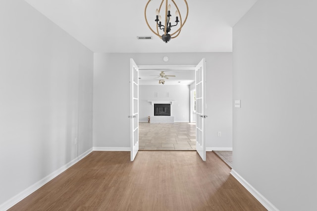 interior space featuring ceiling fan with notable chandelier, light hardwood / wood-style flooring, and french doors