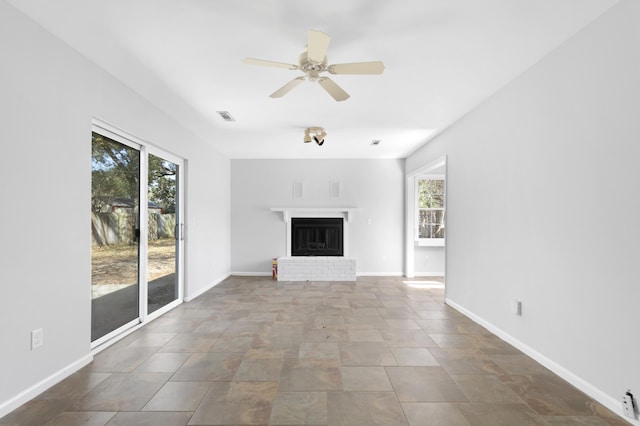 unfurnished living room with a brick fireplace and ceiling fan