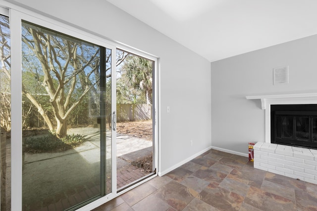 unfurnished living room featuring lofted ceiling and a brick fireplace