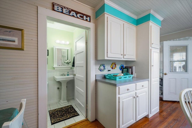 interior space featuring wooden walls, dark hardwood / wood-style floors, and white cabinets