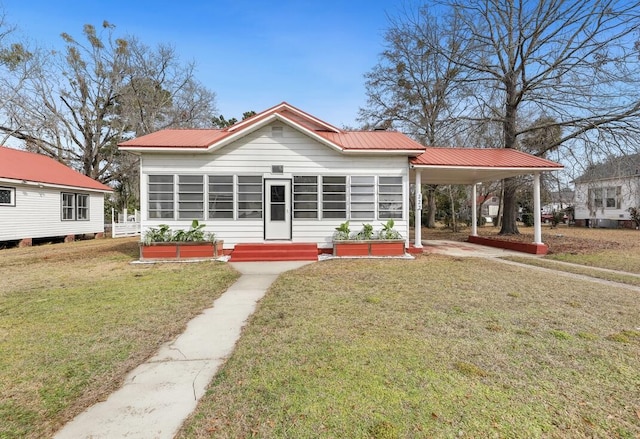 rear view of property featuring a yard, a sunroom, and a carport