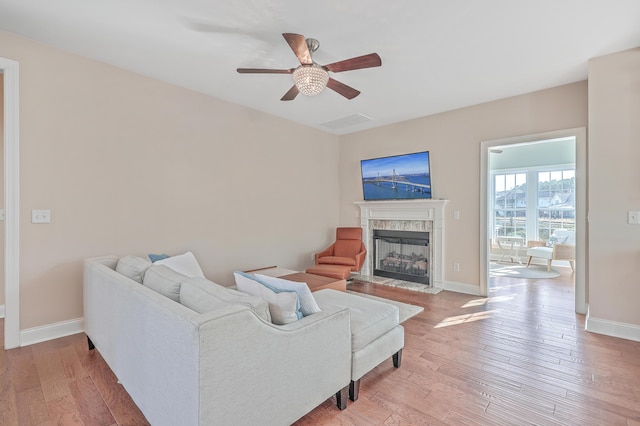 living room with ceiling fan, a fireplace, and wood-type flooring