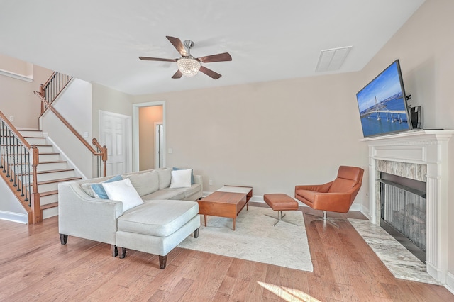 living room with ceiling fan, a fireplace, and light hardwood / wood-style flooring