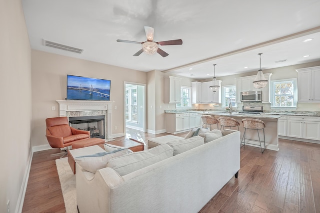 living room featuring a high end fireplace, hardwood / wood-style floors, a wealth of natural light, and ceiling fan