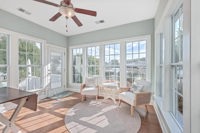 sunroom / solarium with ceiling fan and a water view