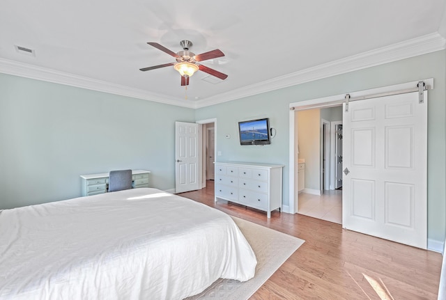 bedroom featuring connected bathroom, ceiling fan, a barn door, light hardwood / wood-style flooring, and crown molding