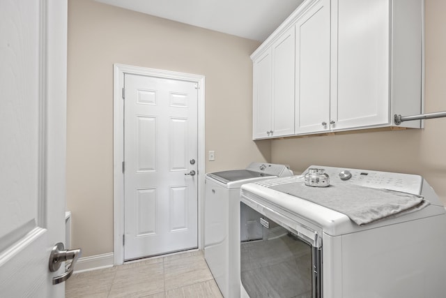 washroom featuring separate washer and dryer, light tile patterned floors, and cabinets