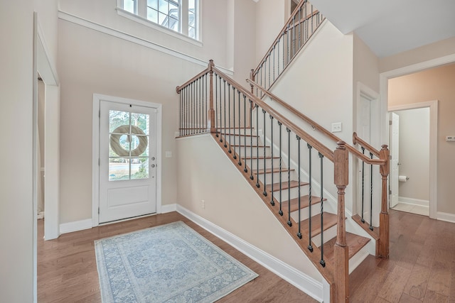 entryway featuring wood-type flooring and a towering ceiling