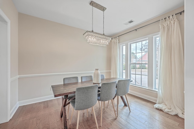 dining room with hardwood / wood-style floors, an inviting chandelier, and plenty of natural light