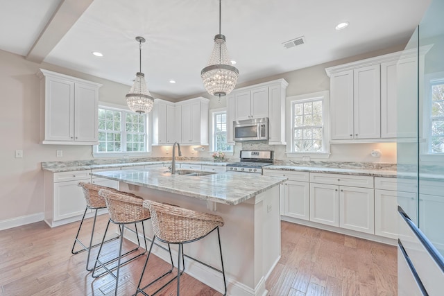 kitchen featuring white cabinets, appliances with stainless steel finishes, an inviting chandelier, and sink