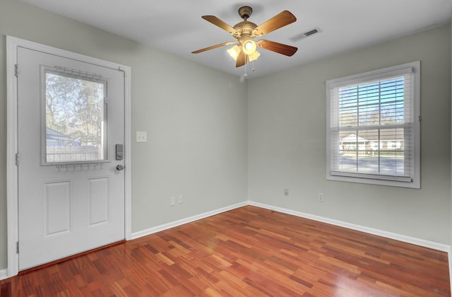 interior space with a ceiling fan, wood finished floors, visible vents, and baseboards