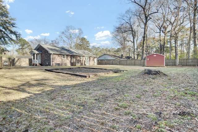 view of yard with a storage shed, a fenced backyard, and an outdoor structure