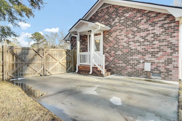 view of side of home featuring crawl space, a gate, fence, and brick siding