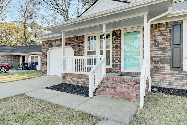 doorway to property featuring an attached garage, a porch, concrete driveway, and brick siding