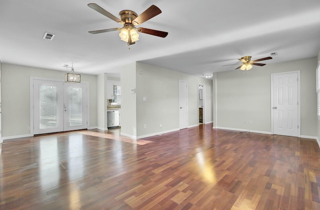 unfurnished living room featuring ceiling fan with notable chandelier, wood finished floors, visible vents, and baseboards