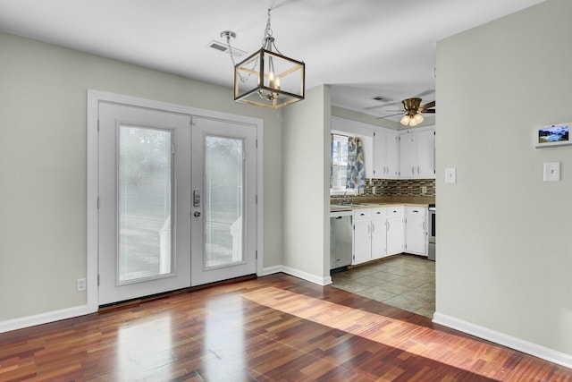 interior space with stainless steel appliances, a sink, white cabinets, french doors, and backsplash