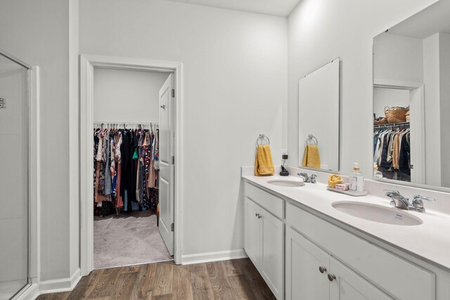 bathroom with dual vanity, a shower with door, and wood-type flooring