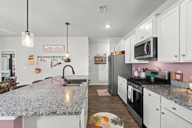 kitchen featuring white cabinets, sink, dark wood-type flooring, appliances with stainless steel finishes, and a kitchen island with sink