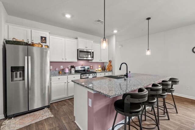 kitchen with stainless steel appliances, a center island with sink, white cabinets, sink, and dark wood-type flooring