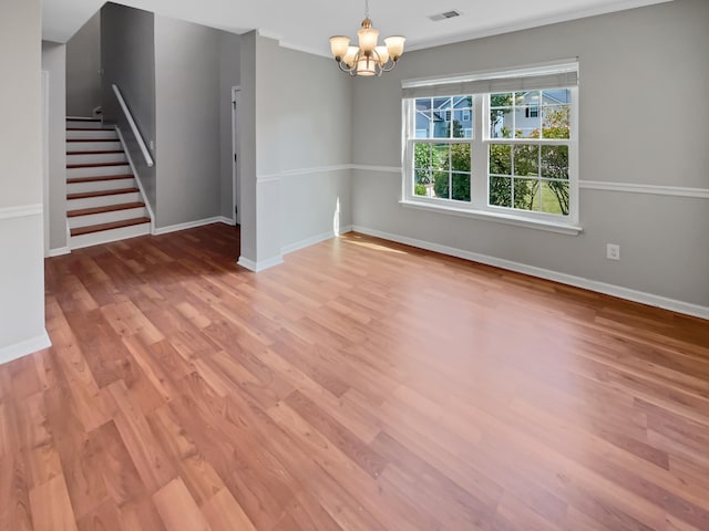 spare room with hardwood / wood-style flooring and a notable chandelier