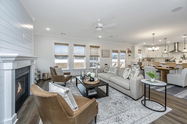 living room featuring hardwood / wood-style floors, ceiling fan with notable chandelier, and ornamental molding