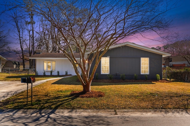 view of front of house with fence, a lawn, and brick siding