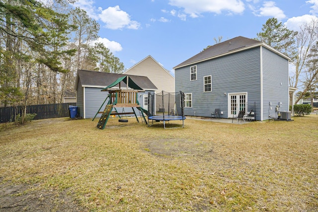 back of house featuring a trampoline, a yard, central AC unit, a patio area, and a playground