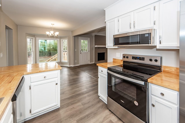 kitchen with hanging light fixtures, butcher block counters, white cabinets, and appliances with stainless steel finishes