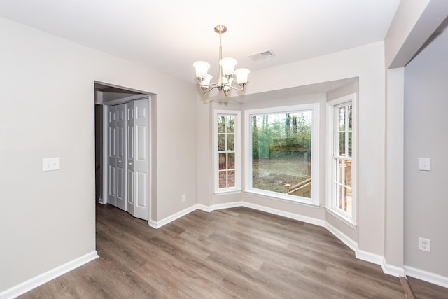 unfurnished dining area featuring wood-type flooring and an inviting chandelier