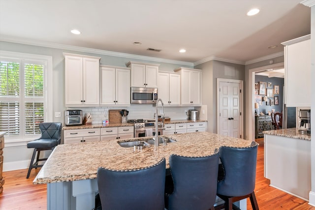 216 Foxbank Plantation Blvd, Moncks Corner, SC 29461 - kitchen with stainless steel microwave, a sink, light wood-style flooring, a kitchen bar, and recessed lighting
