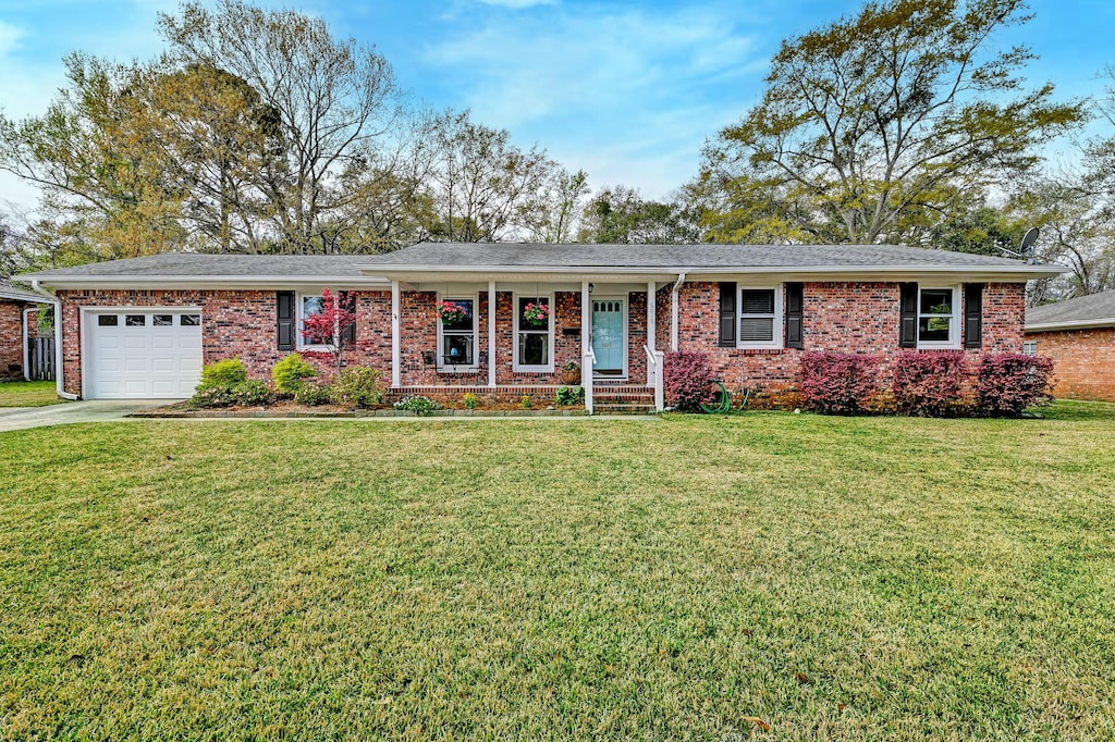 ranch-style home with an attached garage, concrete driveway, brick siding, and a front yard