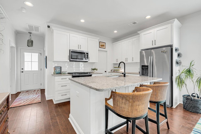 kitchen with sink, a kitchen island with sink, stainless steel appliances, a kitchen breakfast bar, and white cabinets