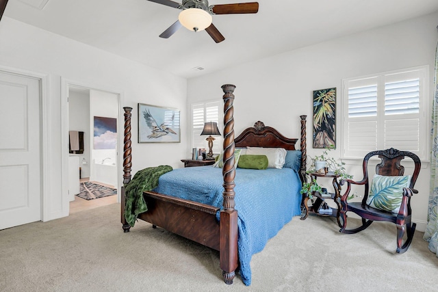 bedroom with ensuite bath, light colored carpet, and ceiling fan