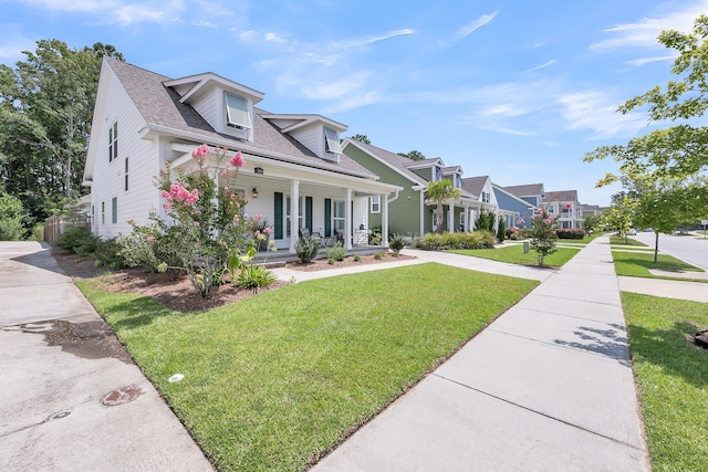 cape cod house featuring covered porch and a front lawn