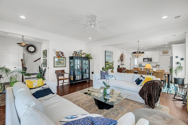 living room featuring dark wood-type flooring, ornamental molding, and ceiling fan with notable chandelier