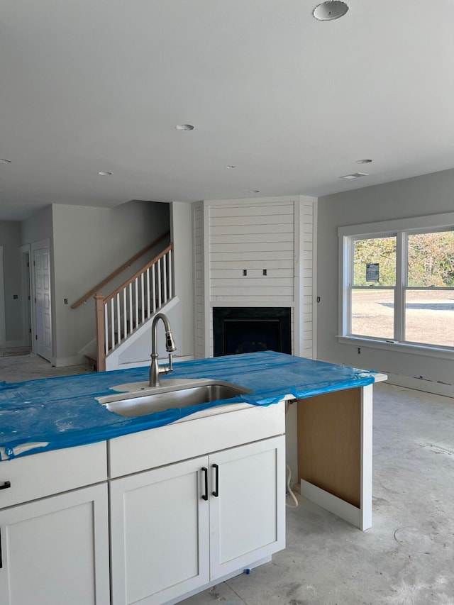 kitchen with white cabinets, a large fireplace, and sink