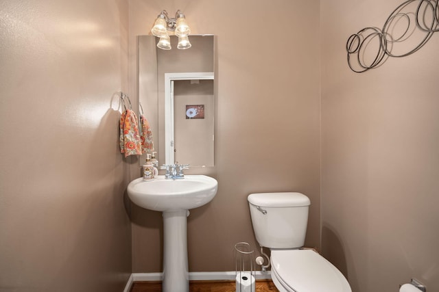 bathroom featuring toilet, baseboards, and a sink