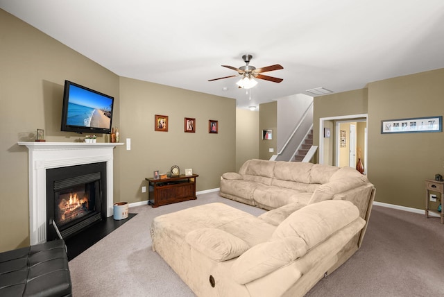 carpeted living area with visible vents, a fireplace with flush hearth, baseboards, and stairway