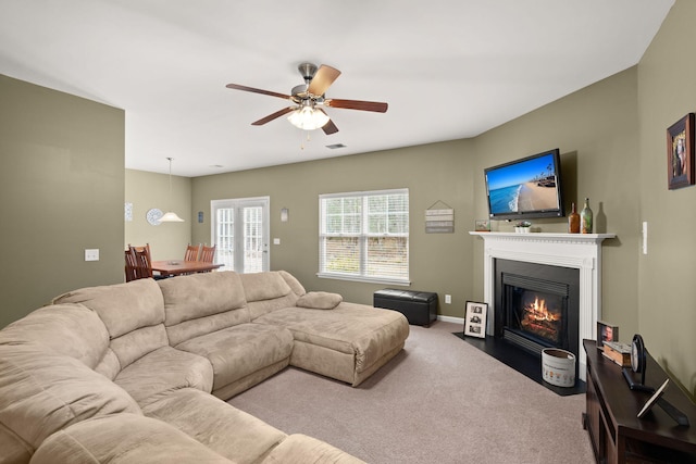 carpeted living room with baseboards, a fireplace with flush hearth, and a ceiling fan