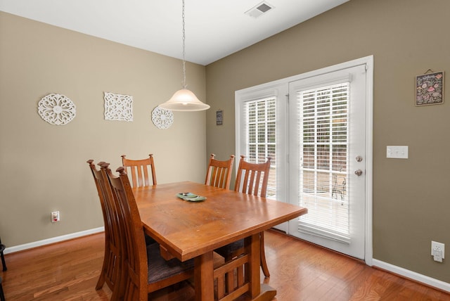 dining area featuring visible vents, light wood-style flooring, and baseboards