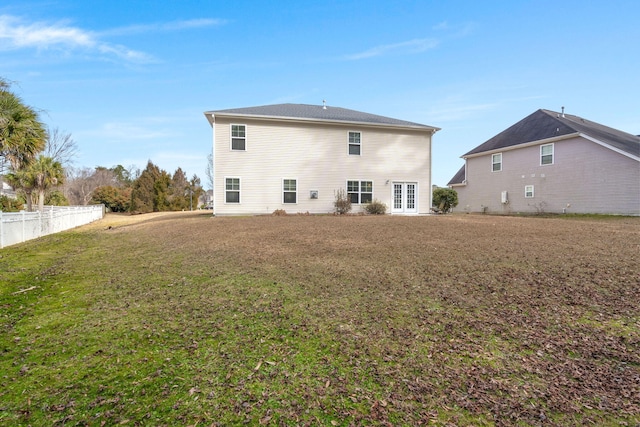 rear view of house with a lawn and fence