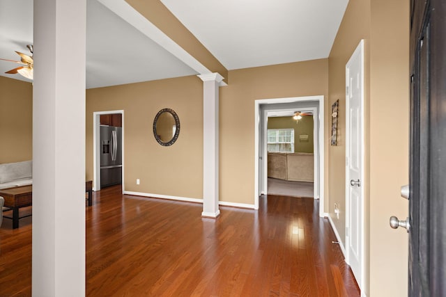 foyer featuring wood finished floors, a ceiling fan, and ornate columns